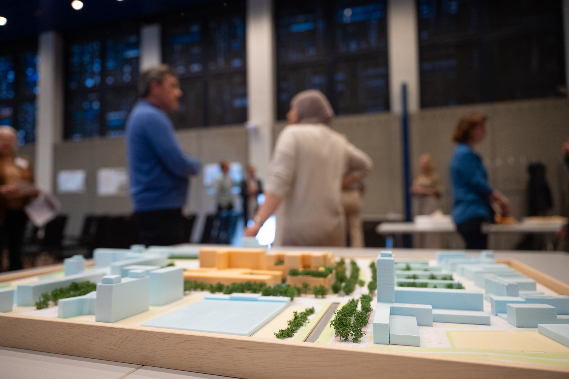 Maquette nieuwbouw OLVG West met twee bezoekers van de bewonersavond erachter