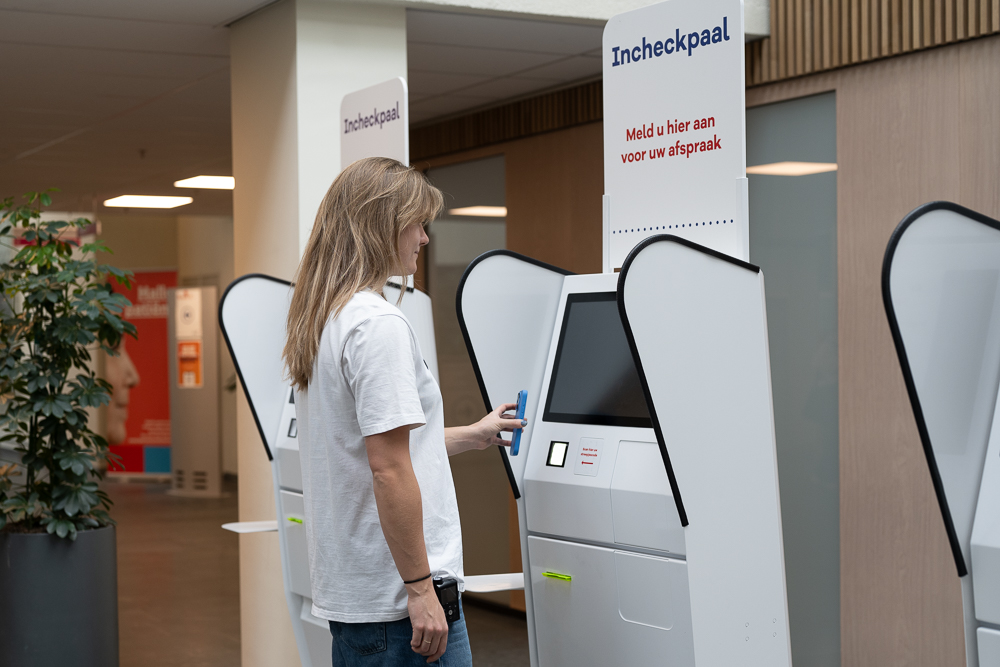 Foto van patiënt die incheckt bij een incheckpaal