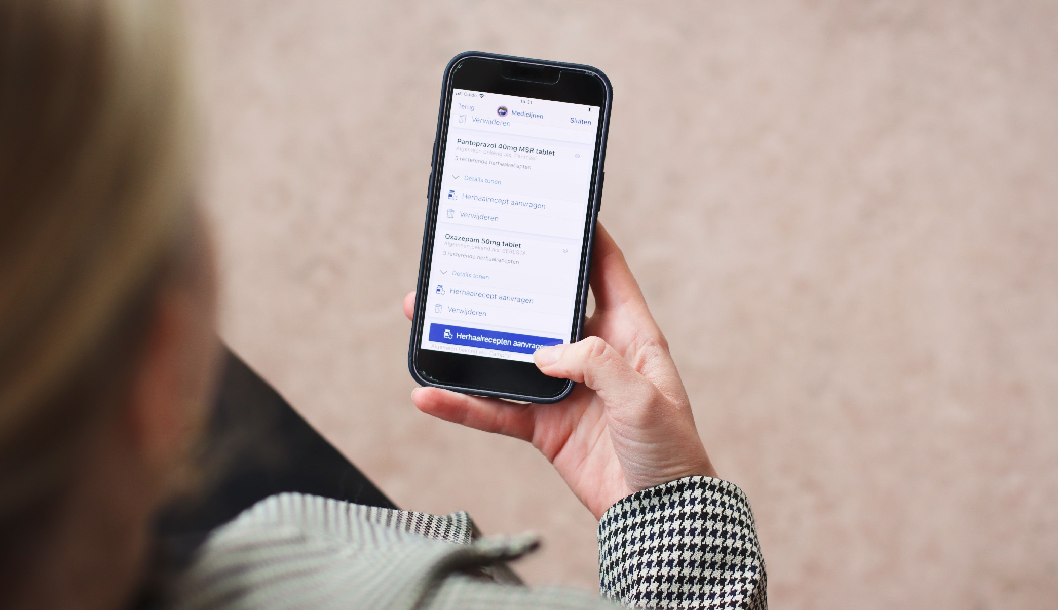 Foto van een vrouw die herhaalrecept aanvraagt op telefoon